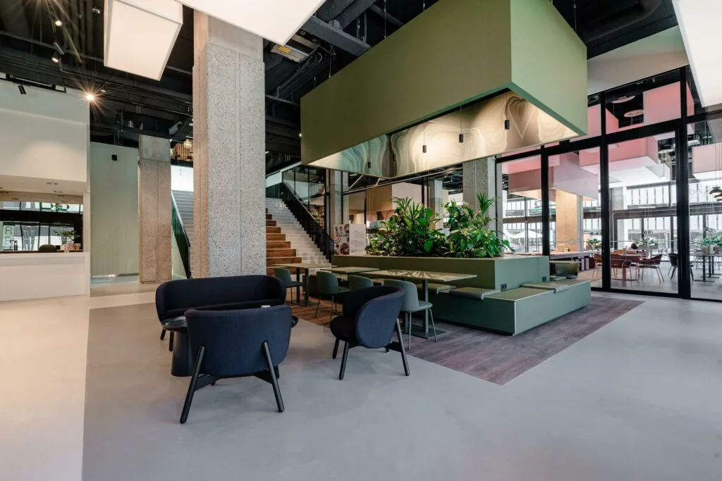 Moderne en open ingerichte lobby aan de Aert van Nesstraat met zitjes, planten en een trap naar de bovenverdieping.